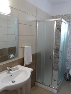 a bathroom with a sink and a glass shower at Proteas Mare Suites in Protaras