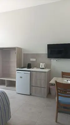 a kitchen with a dishwasher and a table and a tv at Proteas Mare Suites in Protaras