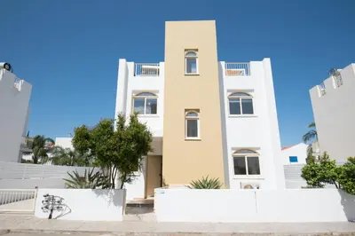 a tall white building with trees in front of it at Villa Pomelo in Protaras