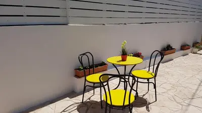two chairs and a table with yellow tables and stools at ZORBAS No 3 in Larnaka