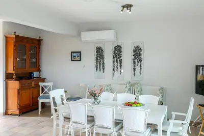 a white dining room with a white table and chairs at Protaras Sirina Waterfront Villa in Protaras