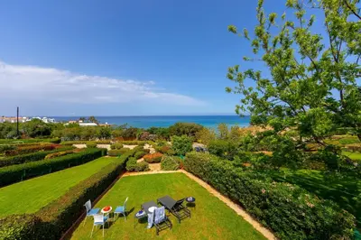 a garden with tables and chairs and the ocean at Protaras Sirina Waterfront Villa in Protaras