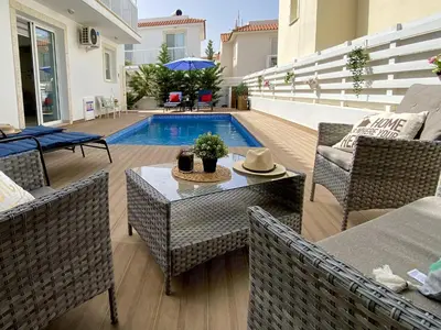 a patio with a pool and chairs and a table at Kalimera Villa Protaras in Protaras