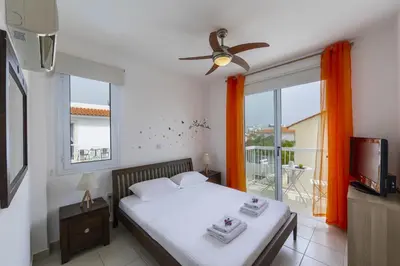 a bedroom with a bed and a tv and a balcony at Kalimera Villa Protaras in Protaras
