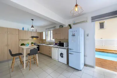 a kitchen with a refrigerator and a table and a pool at Kalimera Villa Protaras in Protaras