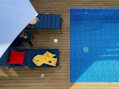an overhead view of a swimming pool with blue chairs and a red pillow at Kalimera Villa Protaras in Protaras