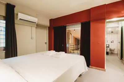 a bedroom with a white bed and a red wall at eins rooms - city center in Limassol