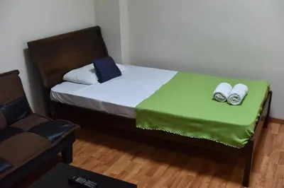 a bed with a green blanket and two shoes on it at Elysium Capital Residence in Nicosia
