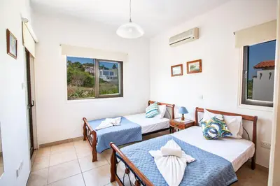 a room with two beds and a table in it at Villa To Perivoli in Protaras