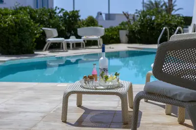 a table with a bottle on it next to a pool at Protaras Villa Kalena Seafront in Protaras