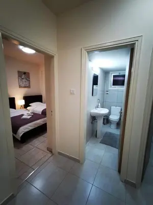 a bedroom with a bed and a bathroom with a sink at Tony’s Boutique Apartment in Larnaka