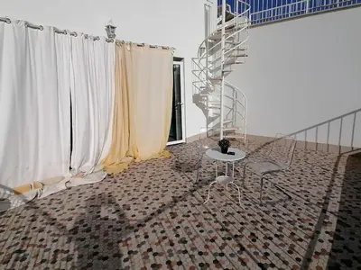 a room with white curtains and a table and a staircase at Limassol sea view studio in Limassol
