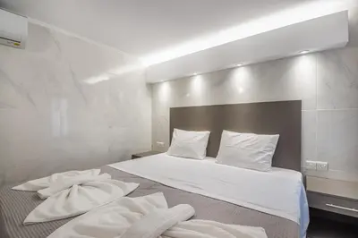 a bedroom with a bed with white sheets and pillows at Gevoni Deluxe Suites in Ayia Napa