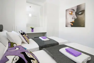 two beds in a white room with purple towels at Villa Megan in Protaras