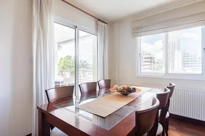 a dining room with a table and chairs and windows at Warm Residence in the heart of the City Center - Balcony & view in Nicosia