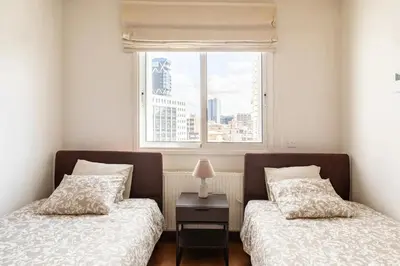 two beds in a room with a window at Warm Residence in the heart of the City Center - Balcony & view in Nicosia