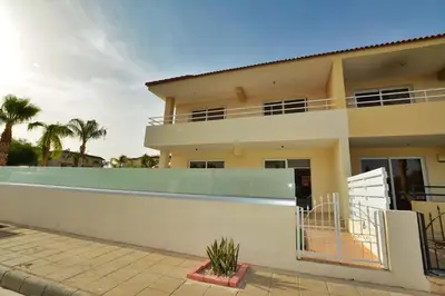 a villa with a swimming pool in front of a house at Nissi Martha Apartment in Ayia Napa