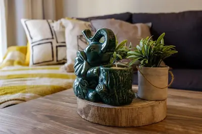 a green statue sitting on a table with plants at The Joy - Centre One Bedroom Flat in Larnaka