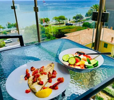 a table with two plates of food and a bowl of salad at Thalassa Sea View Suite in Limassol