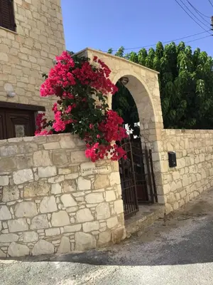 a stone wall with a gate with pink flowers at Salamiou Stone House in Paphos City