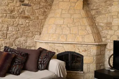 a stone wall with a couch in front of a fireplace at Salamiou Stone House in Paphos City