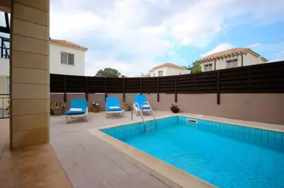 a swimming pool with blue chairs next to a house at Villa Lola in Ayia Napa