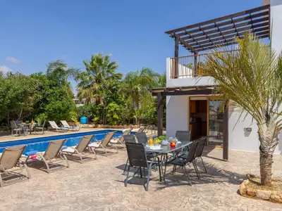 a patio with a table and chairs next to a pool at Angel Villa in Ayia Napa