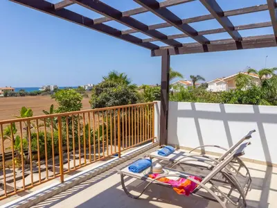 a chair on a balcony with a view of the ocean at Angel Villa in Ayia Napa