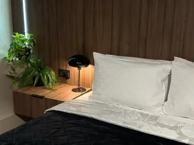 a bed with white pillows and a wooden head board at Levante Holiday Apartments in Larnaka
