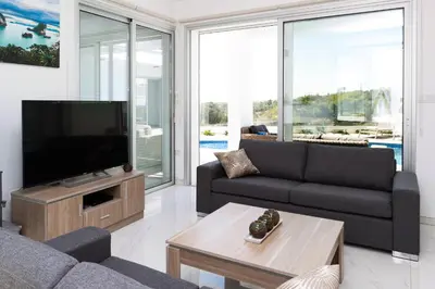 a living room with a tv and a couch and a table at Villa Rubi in Ayia Napa