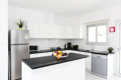 a white kitchen with a bowl of fruit on a counter at Villa Rubi in Ayia Napa
