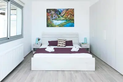 a bedroom with a white bed and a painting on the wall at Villa Rubi in Ayia Napa