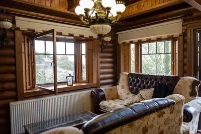 a living room with a leather couch and windows at *2 bdr log house /mountains/Queen bed/fireplace in Gourri