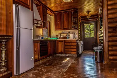 a kitchen with wooden cabinets and a refrigerator at *2 bdr log house /mountains/Queen bed/fireplace in Gourri