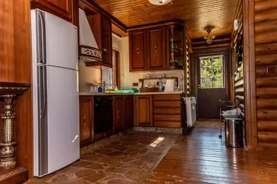 a kitchen with wooden cabinets and a refrigerator at *2 bdr log house /mountains/Queen bed/fireplace in Gourri