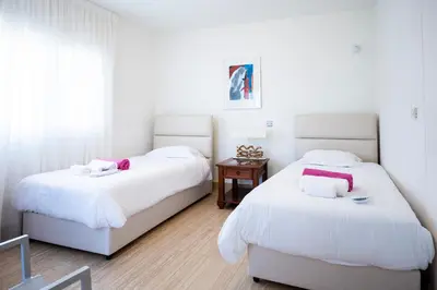 a bedroom with two beds with white sheets and pink accents at AAA SEAVIEW PANORAMA in Pervolia