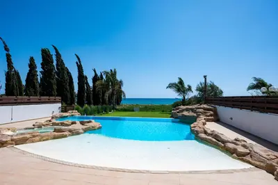 a swimming pool in a yard with trees and the ocean at AAA SEAVIEW PANORAMA in Pervolia
