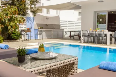 a table with a drink on it next to a swimming pool at Fig Tree Bay Residences 3-Jacuzzi-Hotub -Pool in Protaras