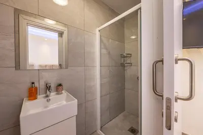 a bathroom with a shower and a sink and a mirror at Fig Tree Bay Residences 3-Jacuzzi-Hotub -Pool in Protaras