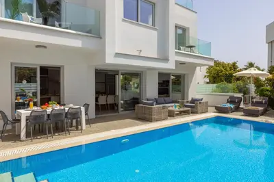 a villa with a swimming pool in front of a house at Fig Tree Bay Residences 3-Jacuzzi-Hotub -Pool in Protaras