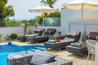 a patio with chairs and an umbrella next to a pool at Fig Tree Bay Residences 5 in Protaras