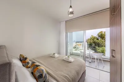 a bedroom with a bed and a large window at Fig Tree Bay Residences 4 in Protaras