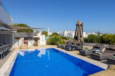 a swimming pool with lounge chairs and an umbrella at Fig Tree Bay Residences 6 in Protaras