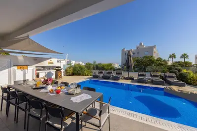 a patio with a table and chairs next to a pool at Fig Tree Bay Residences 6 in Protaras