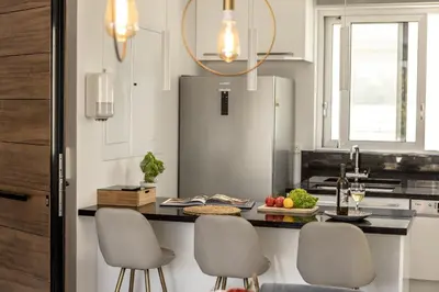 a kitchen with a counter with chairs and a refrigerator at Fig Tree Bay Residences 6 in Protaras