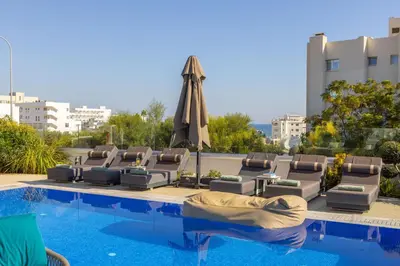 a swimming pool with lounge chairs and an umbrella at Fig Tree Bay Residences 6 in Protaras