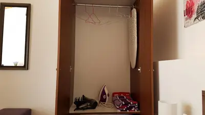 a closet with shoes on a shelf next to a refrigerator at ZORBAS No 2 in Larnaka