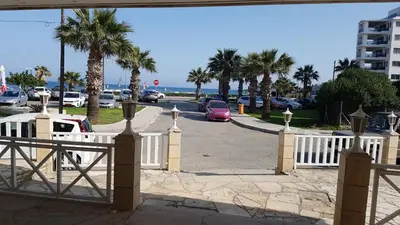 a white fence with palm trees and a parking lot at ZORBAS No 2 in Larnaka