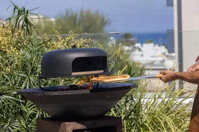 a person is cooking food on a grill at Fig Tree Bay Residences 7 in Protaras