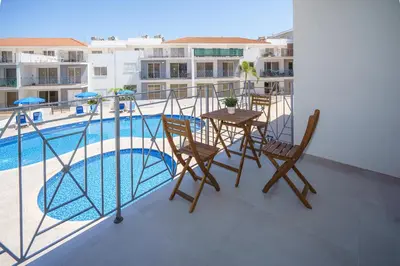 a balcony with a table and chairs and a swimming pool at Emily apartment in Paralimni